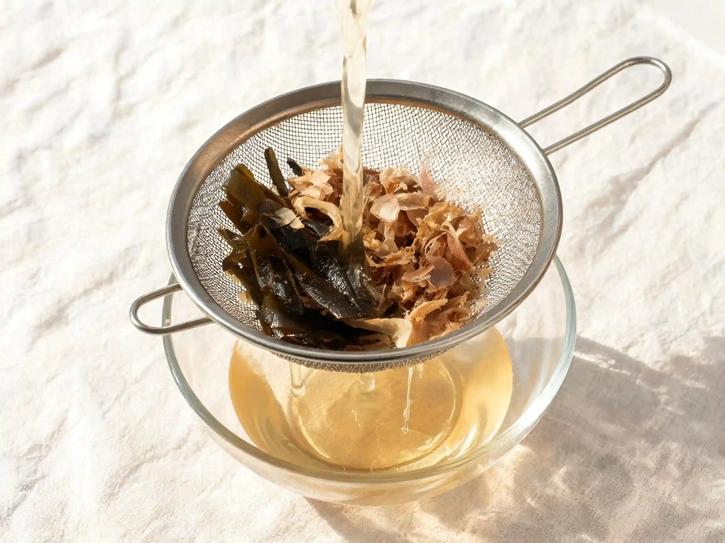 dashi-maison-recette Bouillon dashi maison clair dans une casserole avec kombu et katsuobushi