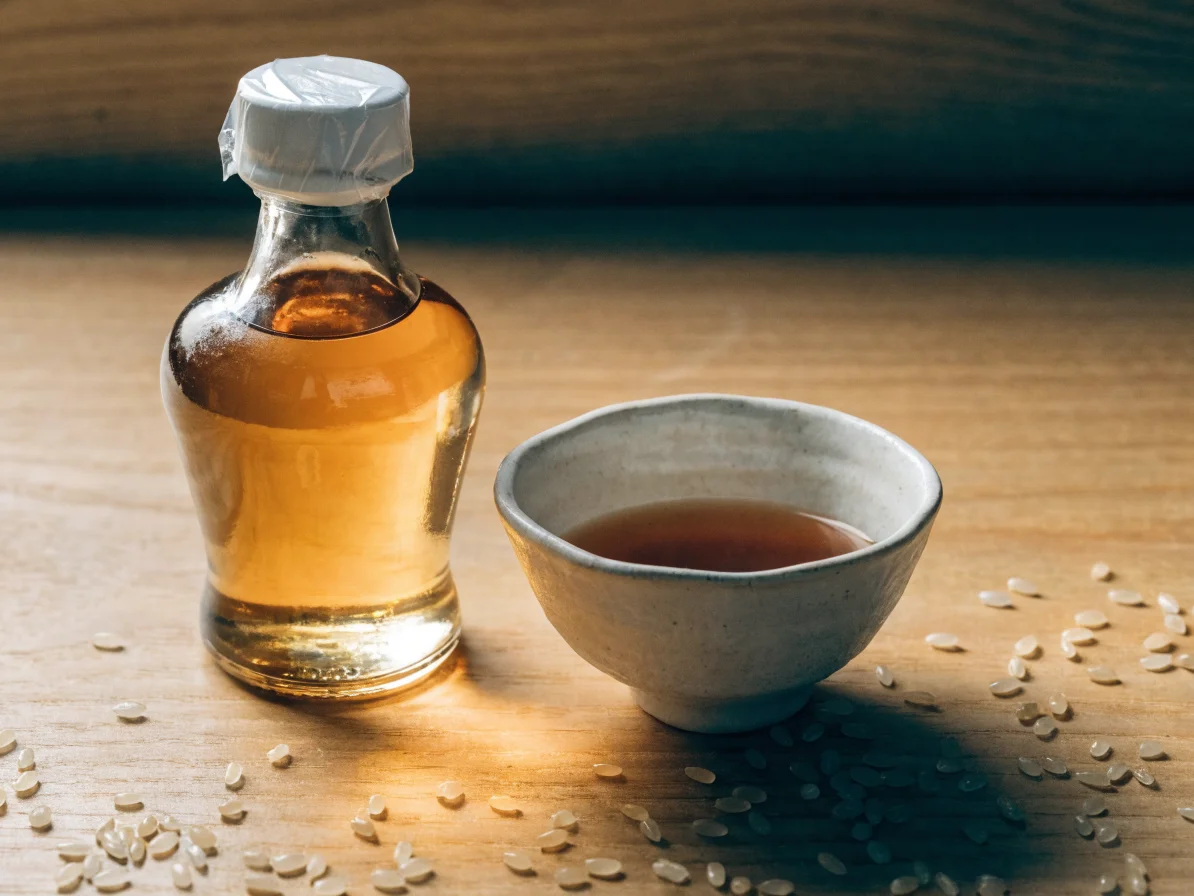 Bouteille de mirin artisanal à côté de grains de riz japonais