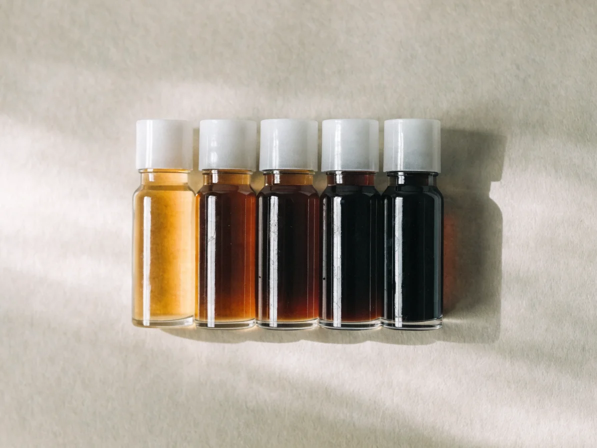 Cinq petites fioles de shoyu japonais de teintes différentes, de l'ambre clair au brun presque noir